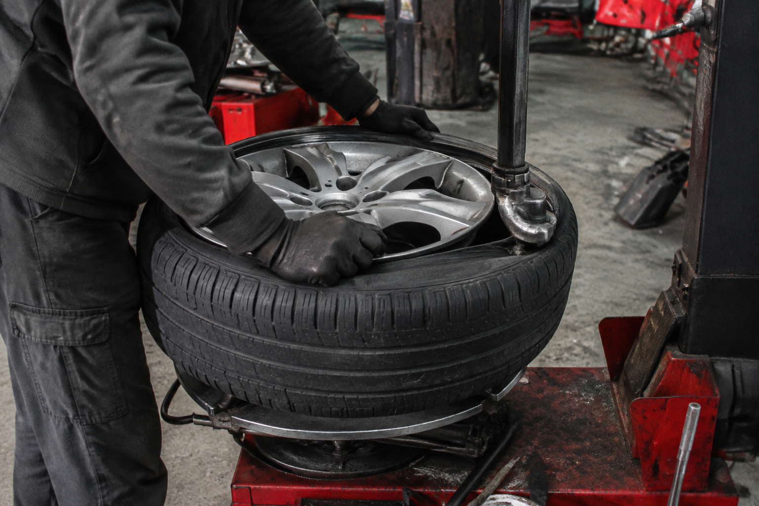 A technician in gloves fitting a tire on a tire changer