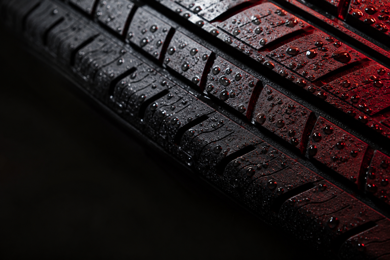 Water droplets on tire tread, lit from the side in red